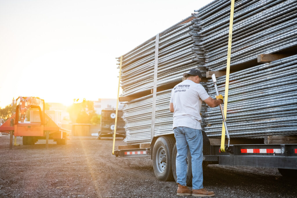 Porper Site Services worker unloading a trailer of factory-new fence section at a commercial work site