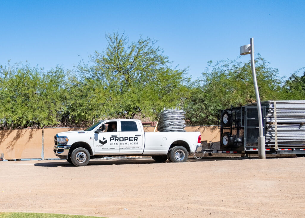 Proper Site Services vehicle delivering new fence sections to a commercial job site